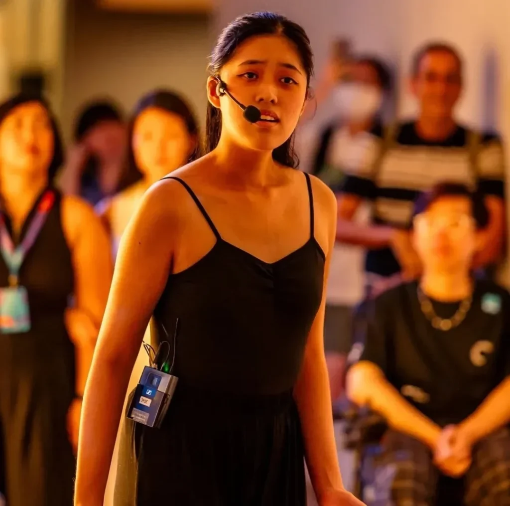 Jade delivering a monologue performance at the National Gallery for the Light to Night Festival 2024. She is wearing a black leotard, her hair tied up neatly in a high ponytail.