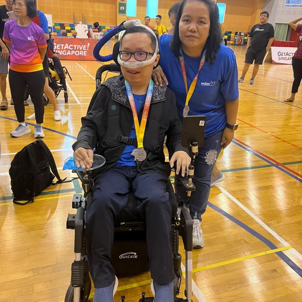 Timothy and his caregiver after a boccia game, each sporting a medal around their necks.