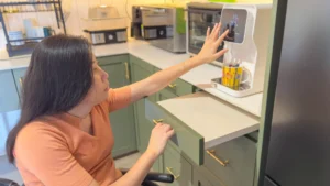 Amanda making a cup of tea, placing the cup on a pull-out drawer in her kitchen.