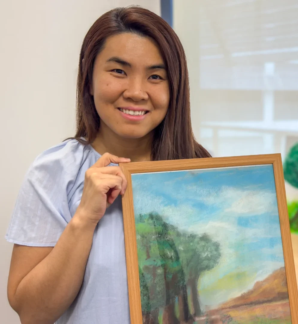 Amanda Yip, holding up one of their artworks (currently untitled).