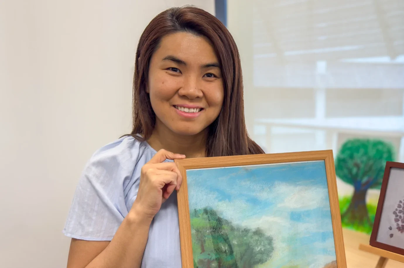 Amanda Yip, holding up one of their artworks (currently untitled).