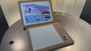 Tactile art piece made of wood pieces that have laser-engraved lines, allowing the user to feel the image. It is displayed in the form of an assembled puzzle piece, with the various blocks put together to depict the artwork in its entirety.